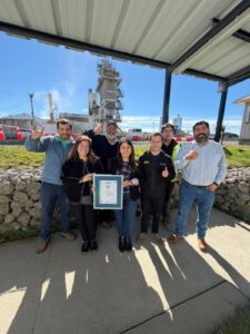 Equipo de Bitumix Austral posando con el certificado ISO 9001:2015 frente a una planta industrial.