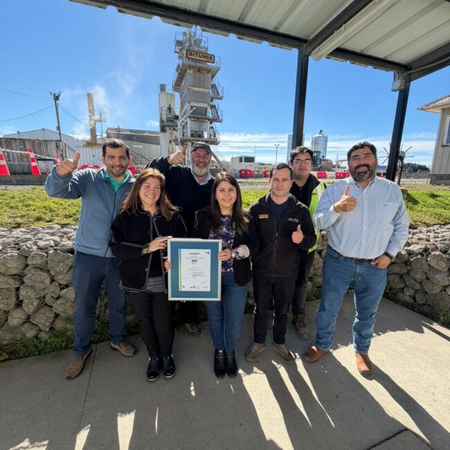 Equipo de Bitumix Austral posando con el certificado ISO 9001:2015 frente a una planta industrial.