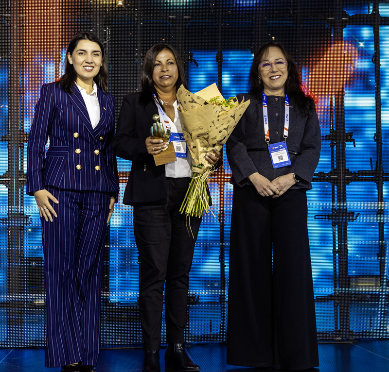 Premiación del Premio Mujer Construye 2026 de la CChC, donde una profesional recibe un trofeo y un ramo de flores durante la ceremonia en escenario.