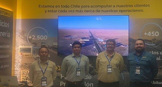 Cuatro integrantes del equipo Bitumix posan en stand de Exponor 2026, frente a pantalla con imagen de carretera en el desierto y paneles informativos sobre servicios para minería.
