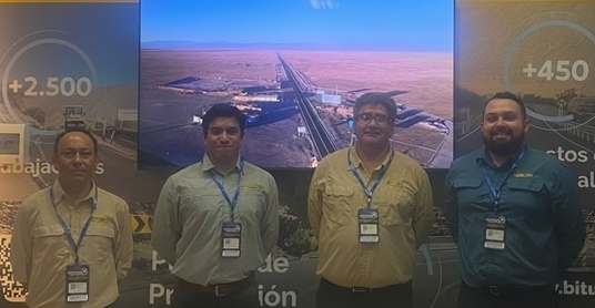 Cuatro integrantes del equipo Bitumix posan en stand de Exponor 2026, frente a pantalla con imagen de carretera en el desierto y paneles informativos sobre servicios para minería.