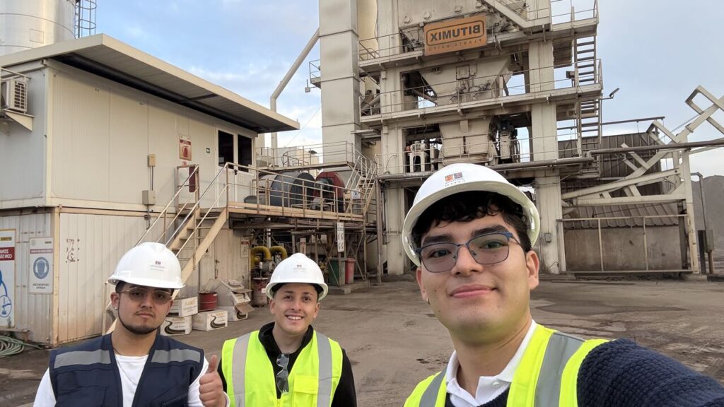 Tres estudiantes del Magíster en Ciencias de la Ingeniería Civil de la Universidad Técnica Federico Santa María, equipados con casco y chaleco de seguridad, durante una visita técnica a la Planta Maipú y al Centro de Desarrollo e Investigación de Bitumix, con instalaciones industriales al fondo.