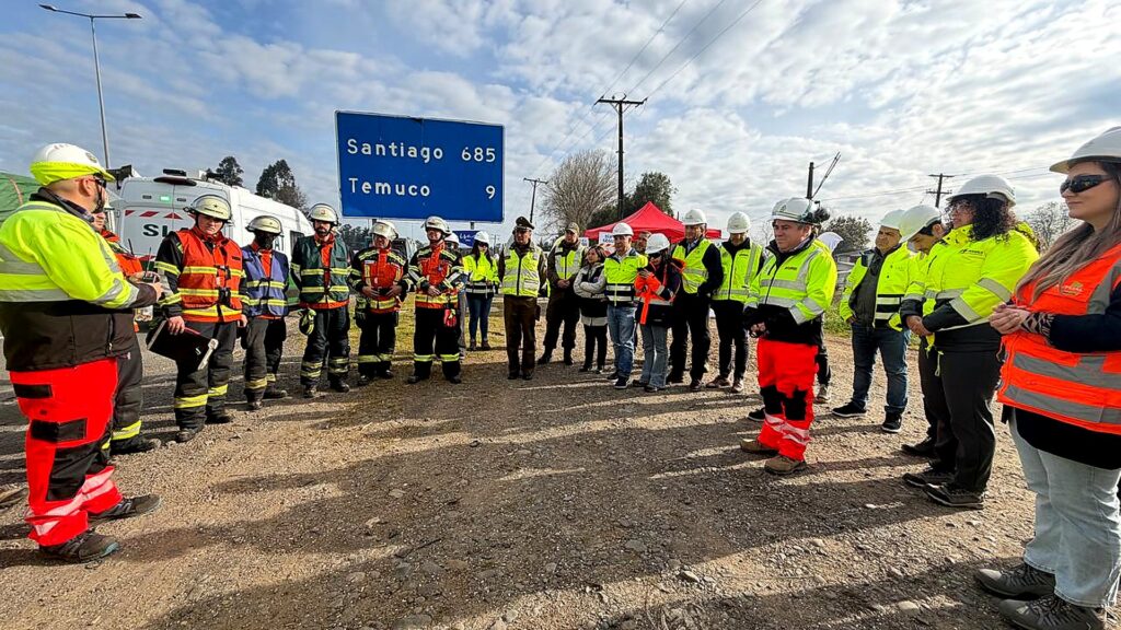 Grupo de trabajadores y profesionales reunidos en una capacitación de seguridad y respuesta ante emergencias en terreno, junto a una ruta de la Región de La Araucanía.